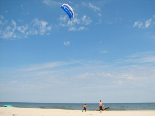 Chałupy - plaża człowiek menewrujący spadochronem zwanym też latawcem używanym do urpawiana KITESURFINGU czyli pływaniu na desce ze spadochornem bez żagla