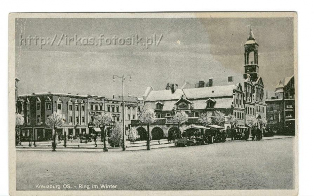 Rynek kluczborski zima- widok z południowego-zachodu. Widoczny ratusz i otaczajace go zabytkowe kamieniczki. Przed ratuszem bubki kramarskie. Około 1930 roku. #Kluczbork #Kreuzburg #Pocztowka