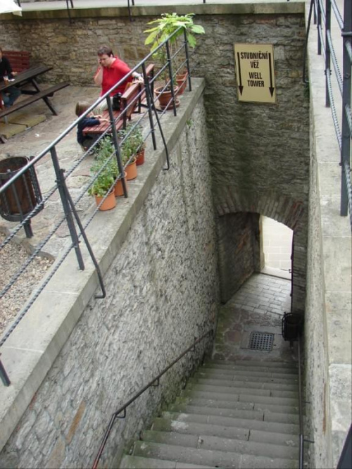 Na prawo od kasy prowadzš w dół schody, którymi dochodzi się do miejsca zwanego Studniční vě (Wieża Studzienna). Wewnatrz można zerknšć (przez kratę) w otchłań zamkowej studni (78 m głębokosci, dzięki oswietleniu widać cała).