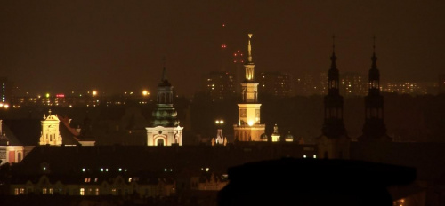 Nocny widok zrobiony przy maksymalnym zoomie optycznym gdzie z którego z bloków na poznańskich Ratajach.Na pierwszym planie widzimy Ratusz na Starym Rynku i fragment Fary,a w tle bloki i wieże na Pištkowie.